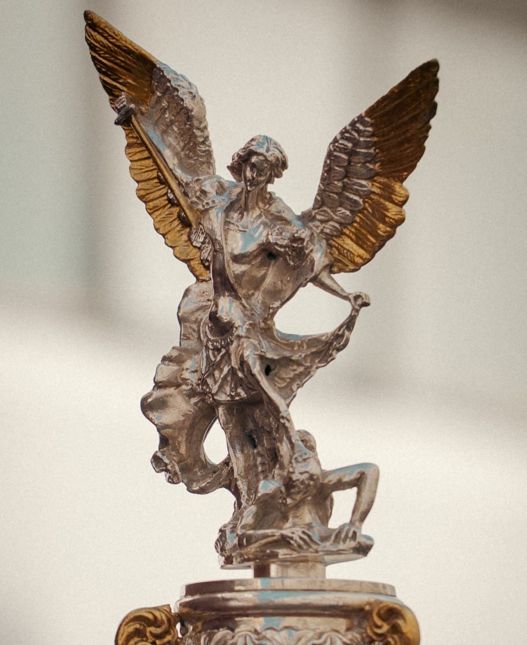 Figura alada de plata y oro que remata la pértiga del banderín.